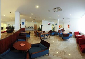 Un vestíbulo de hotel con zonas de estar, una recepción e indicación de salida.