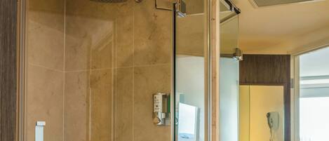 A modern bathroom with a glass-enclosed shower, a vanity with a marble countertop, and a large mirror reflecting the room.