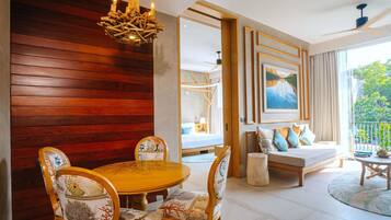 A modern living room with a wooden wall, a round dining table with chairs, a sofa with cushions, and a painting on the wall.