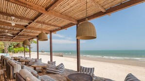 A beachside lounge with wooden furniture, hanging lamps, and a view of the ocean. - SO/ Sofitel Hua Hin (Cha-am)