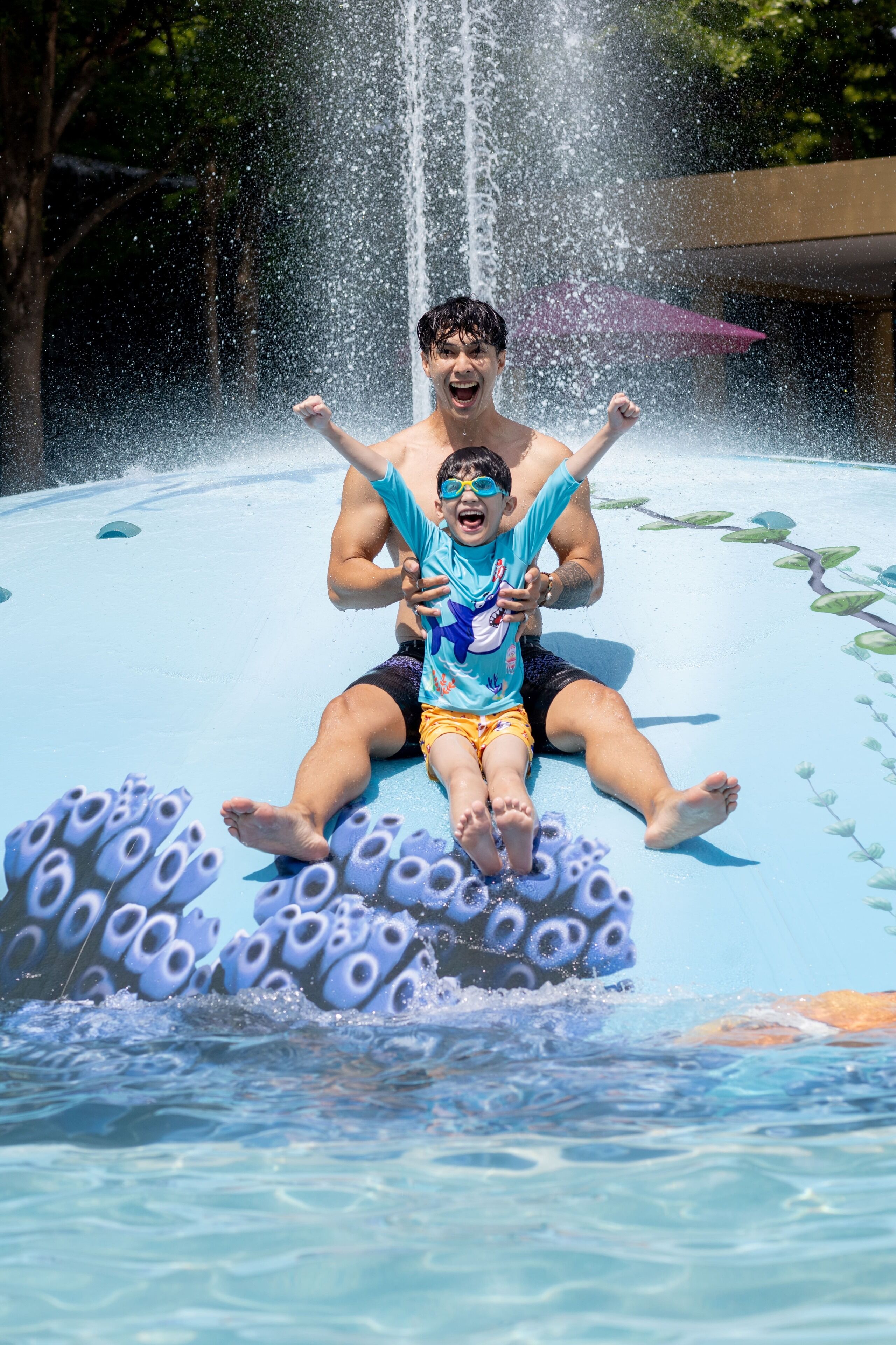 Tobogán acuático con un niño y un adulto en la parte superior, agua salpicando.