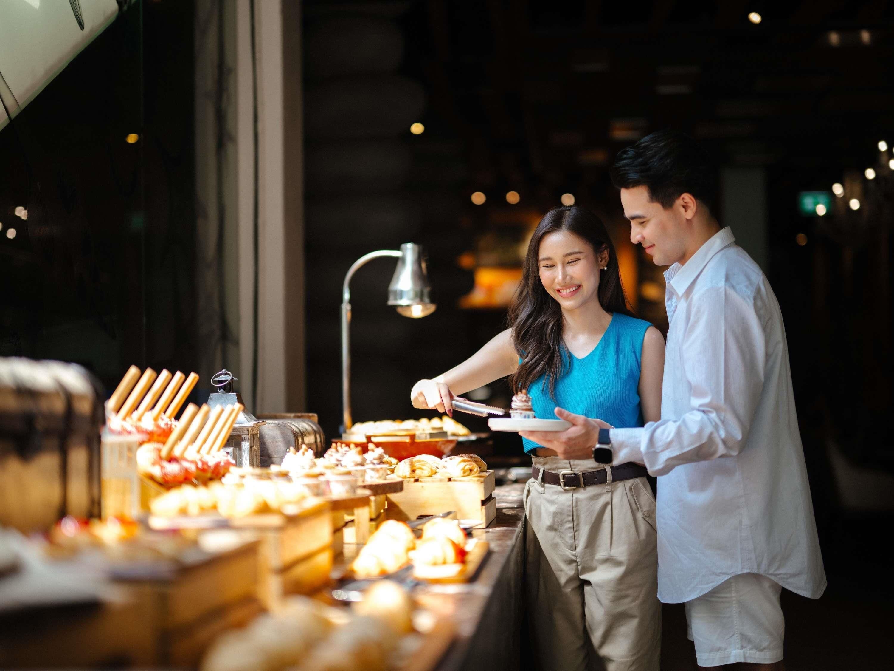 A buffet with various food items and a person serving food.