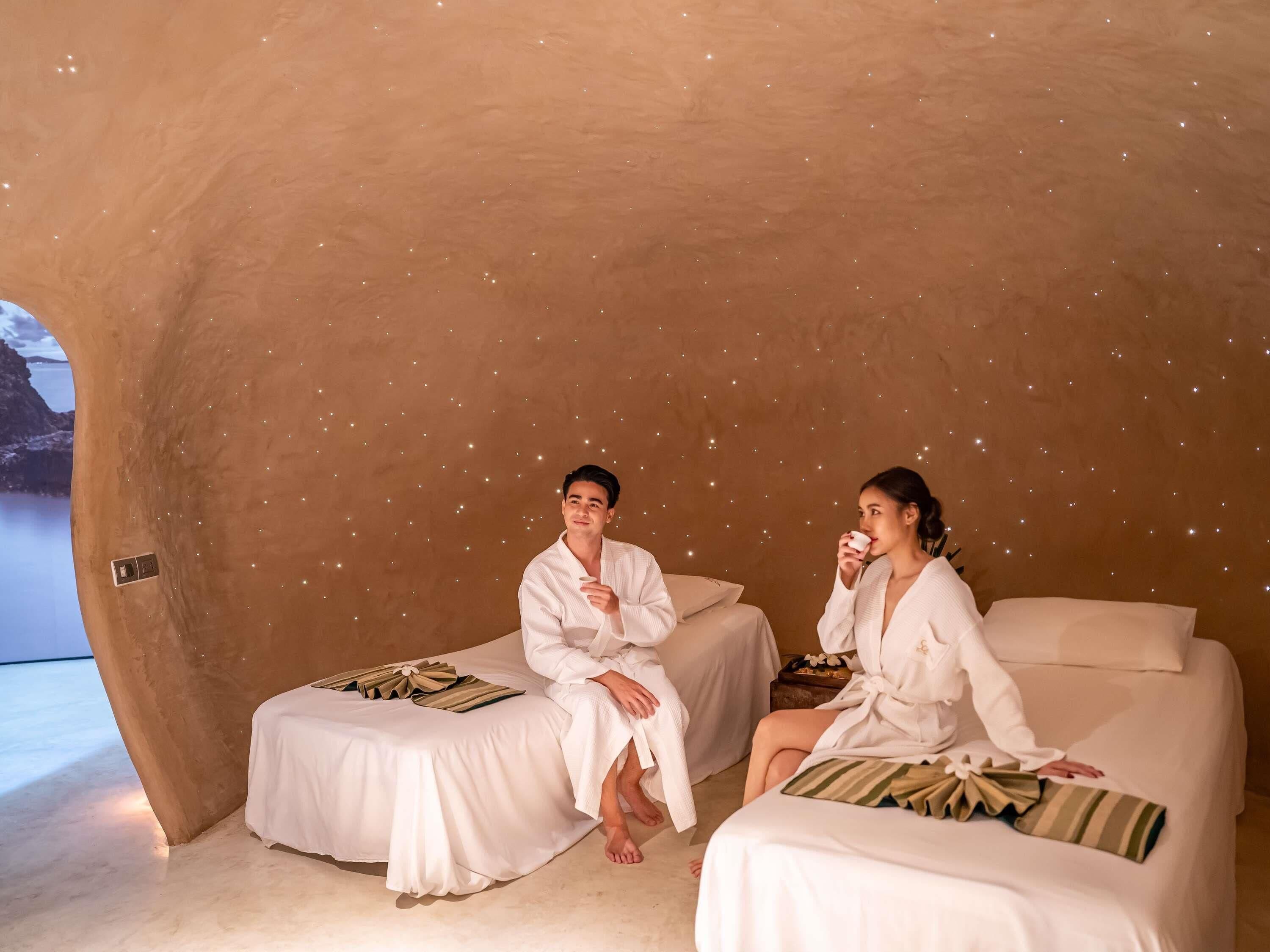 Deux lits de massage, recouverts de draps blancs, un plafond étoilé et une vue sur la mer.