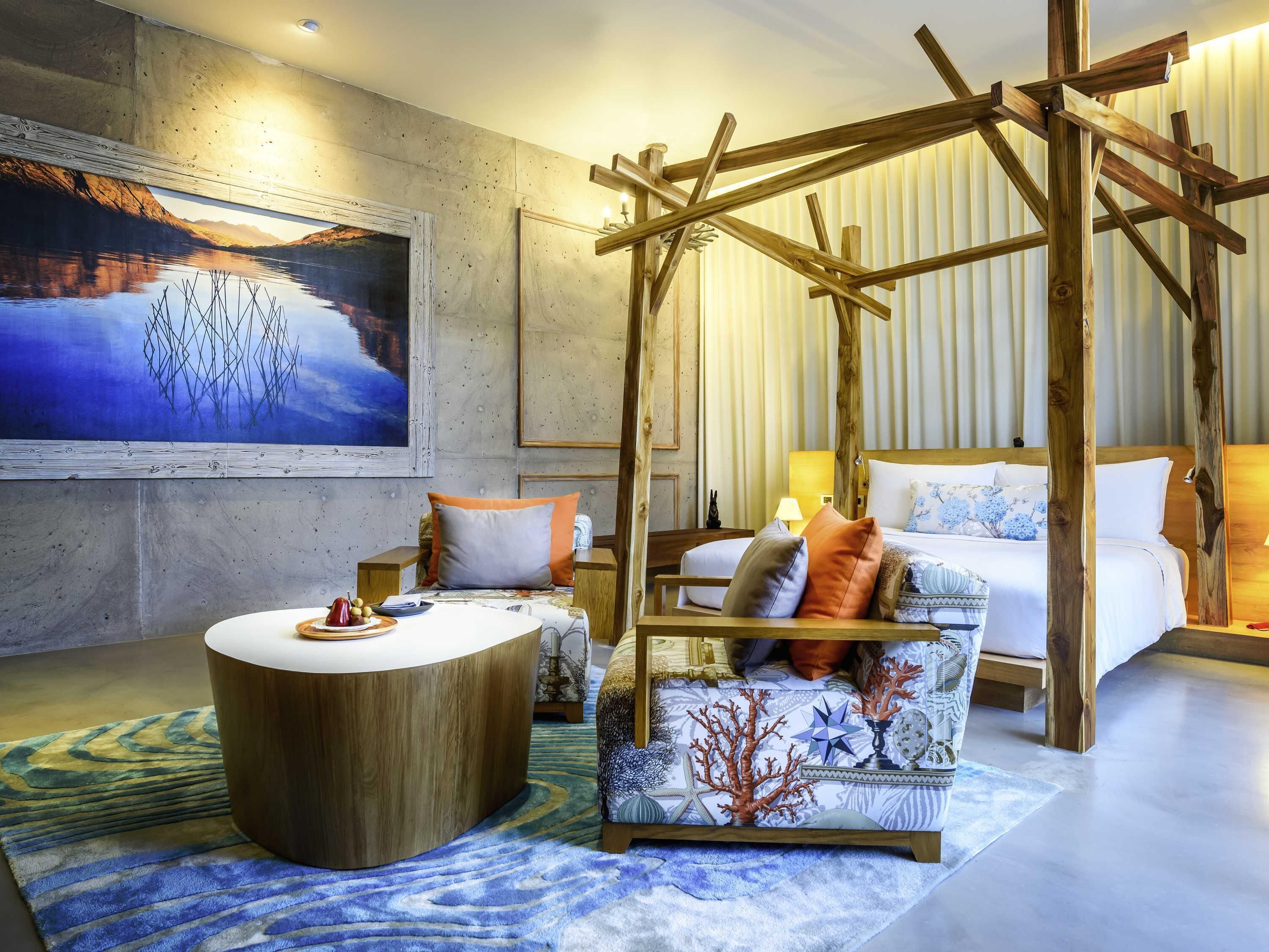 A room with a bed, a wooden chair, a round table, and a painting of a landscape.