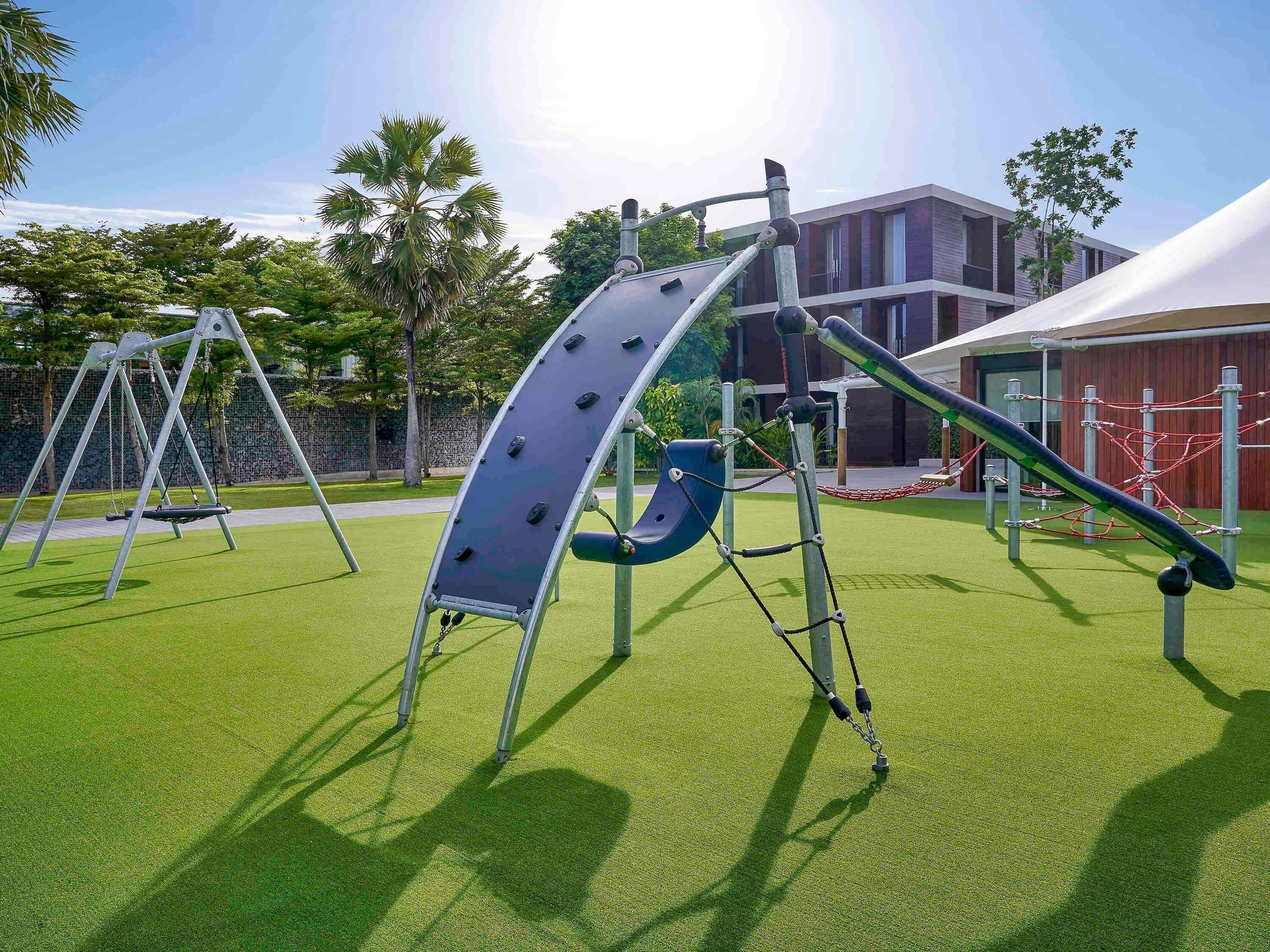 A playground with swings, a climbing structure, and a slide.