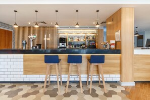 Un espace bar avec un comptoir, des tabourets et un assortiment de bouteilles.