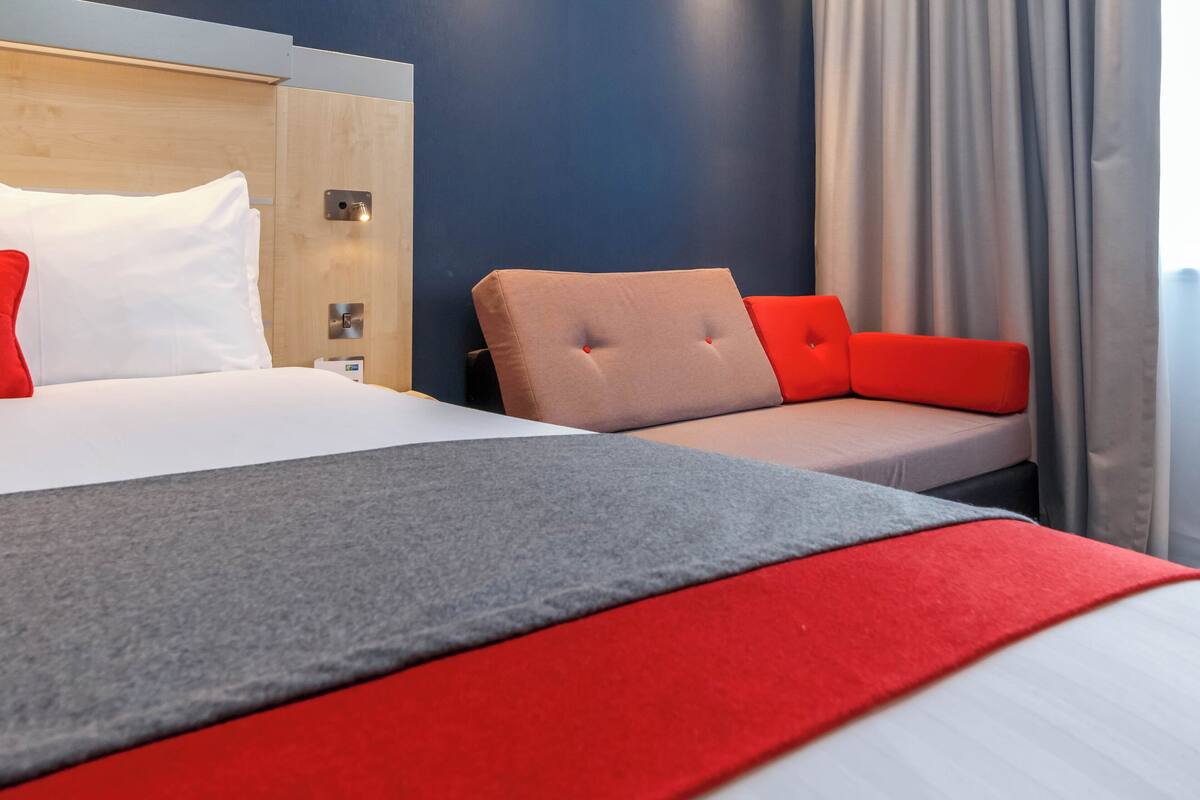 Una habitación de hotel con una cama, un sofá y una mesita de noche.