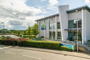 Edificio de Holiday Inn Express con un diseño moderno, que cuenta con ventanas amplias y un asta de bandera.