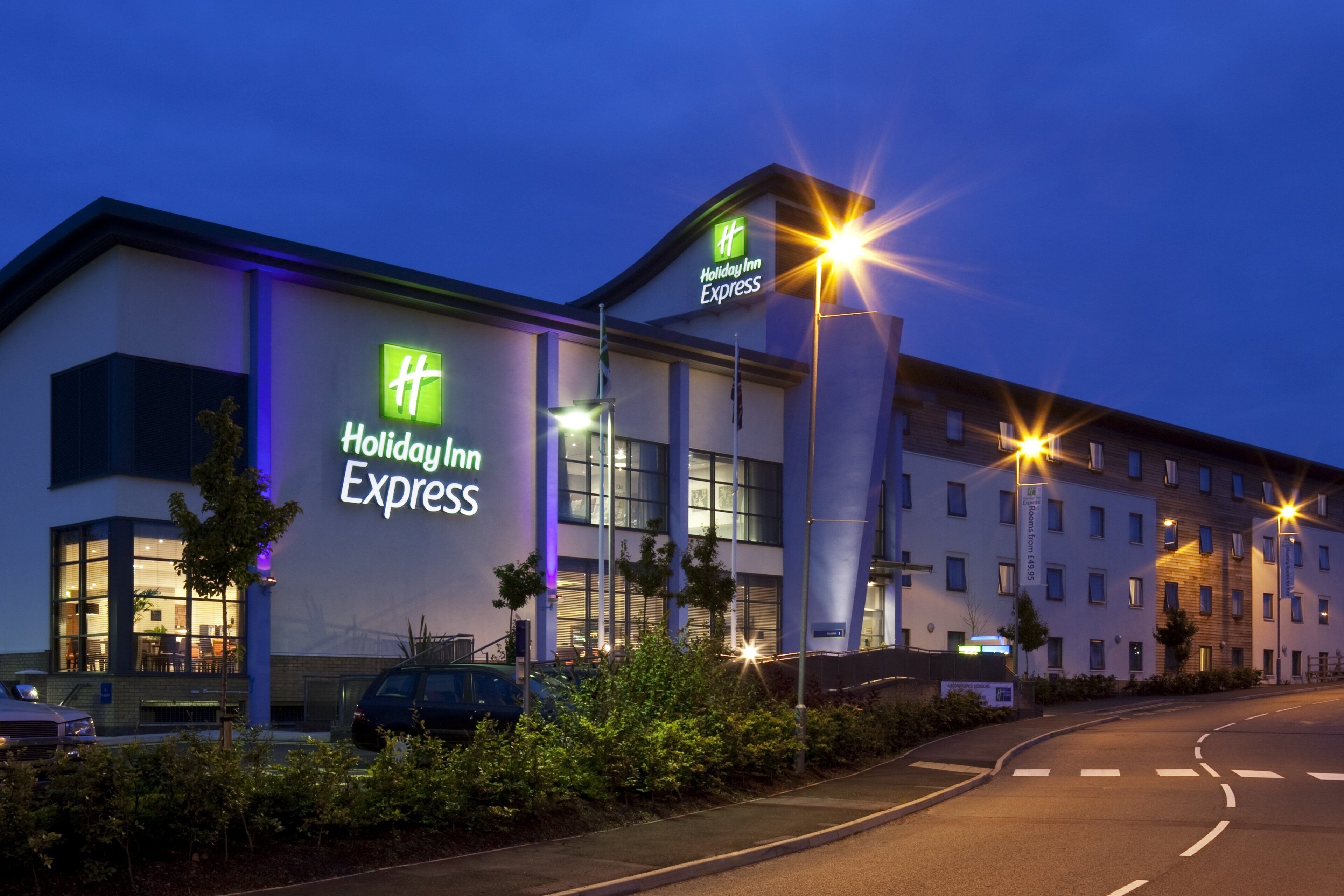 Edificio de Holiday Inn Express con diseño moderno, destacando amplias ventanas y una señalización llamativa.