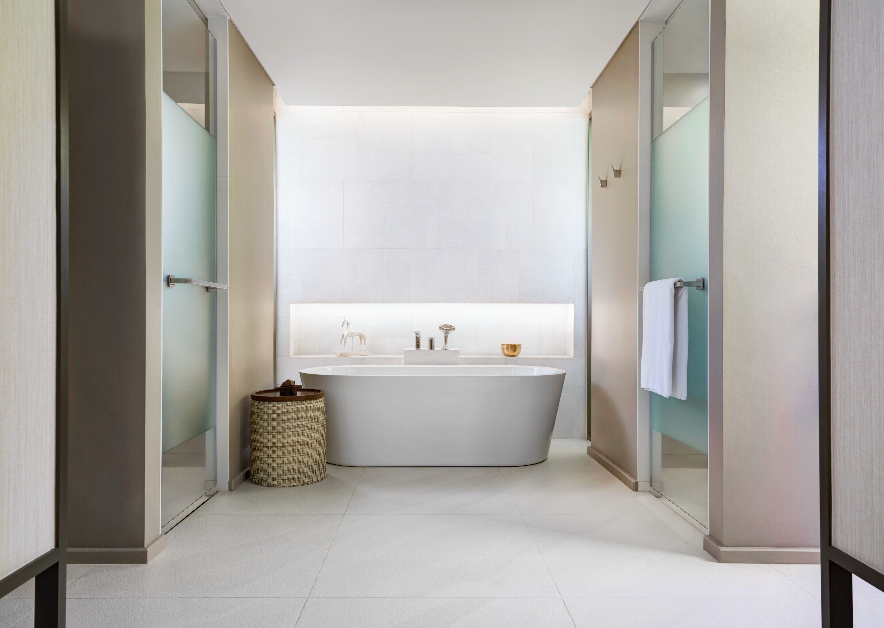A modern bathroom with a freestanding bathtub, a glass shower enclosure, and a wicker basket.