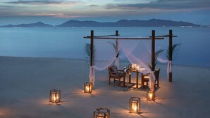 A beachside dining setup with a canopy, tables, chairs, and lanterns. - Santiburi Koh Samui (Koh Samui)
