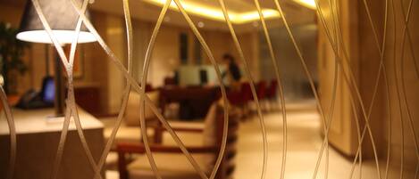 A blurred interior of a hotel lobby with a reception desk and seating area.