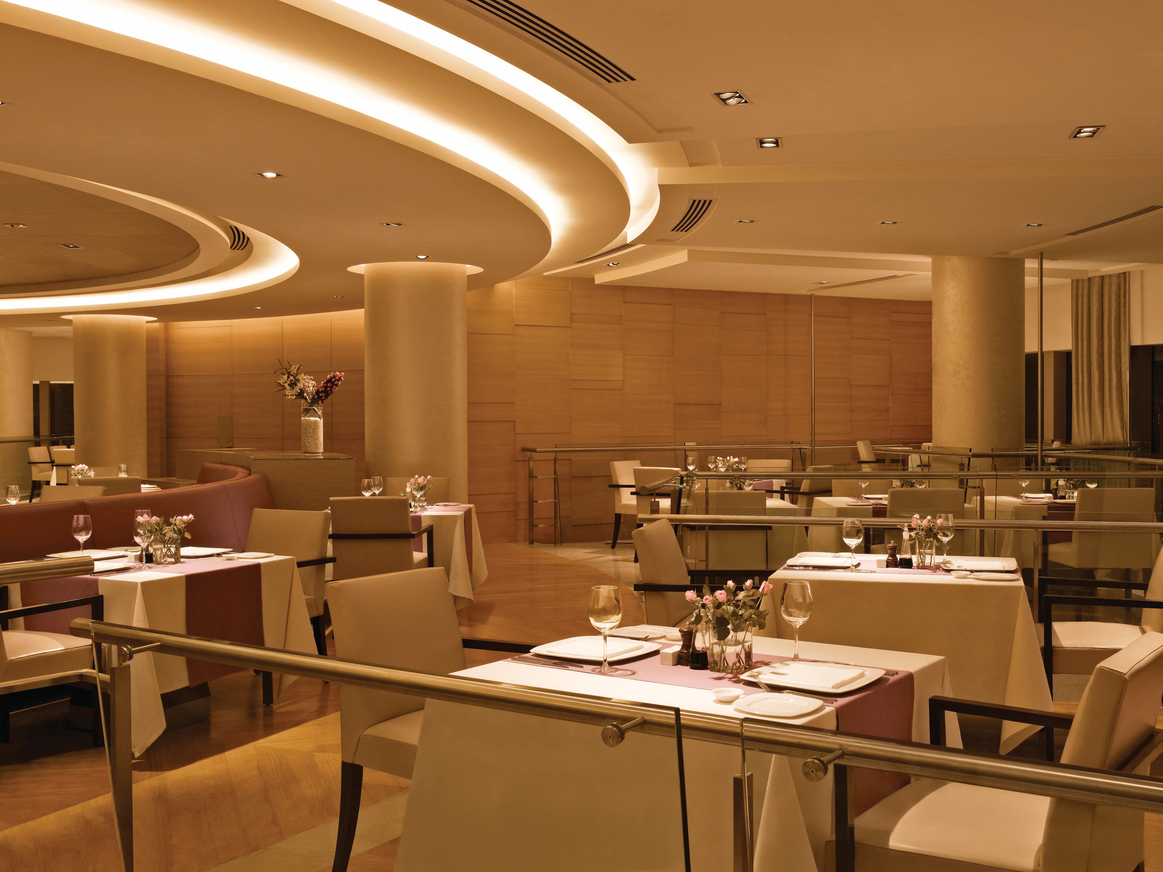 A modern dining area with round tables, glass partitions, and a warm color scheme.