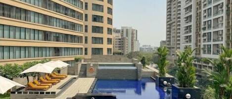 Een buitenzwembad, parasols voor strand/zwembad