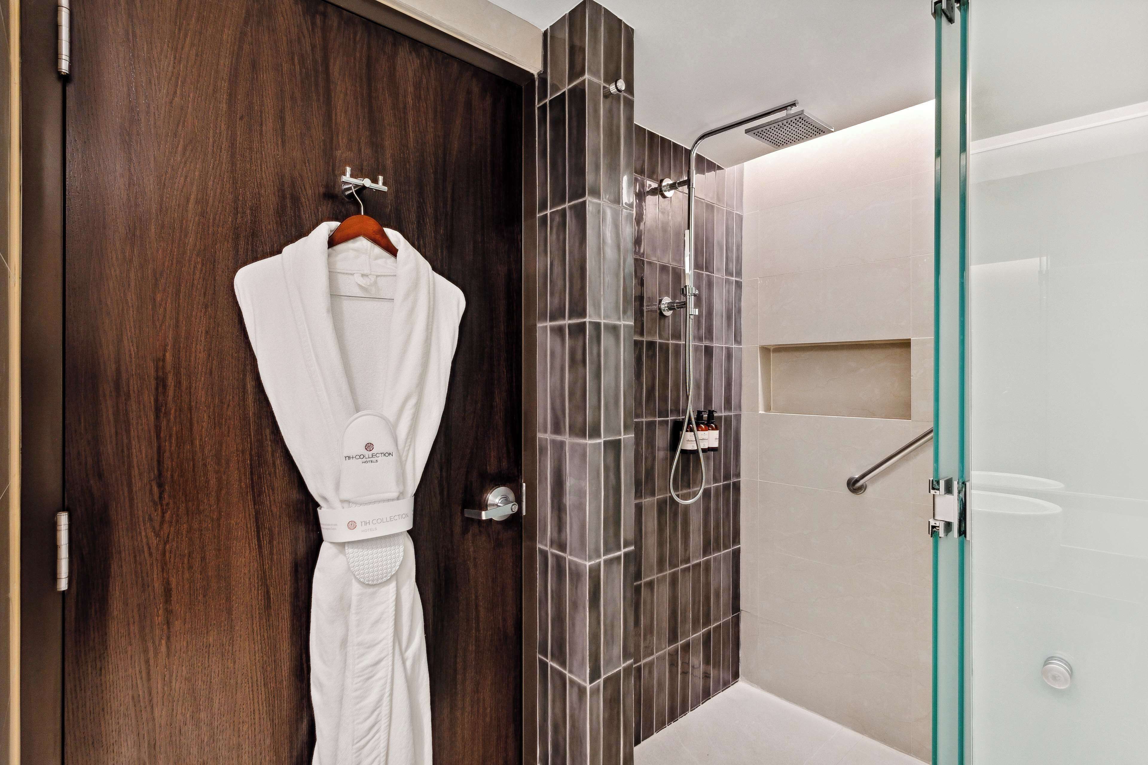 A bathroom with a wooden door, a glass shower enclosure, and a white bathtub.