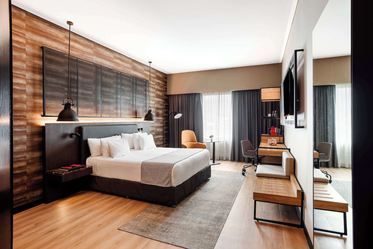 Una habitación de hotel moderna con una cama grande, un escritorio y un televisor.
