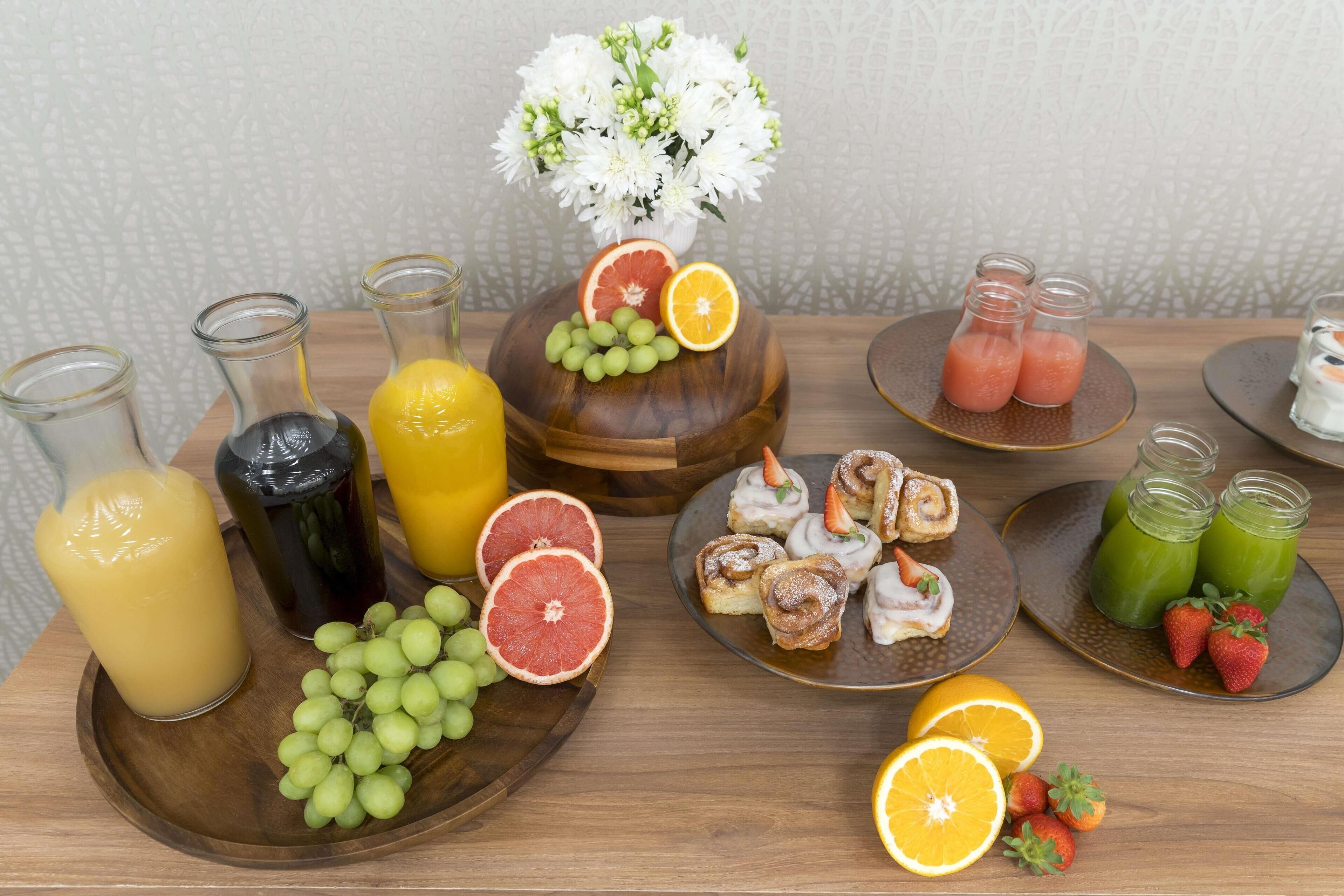 Una mesa de desayuno con diversas frutas, jugos y pasteles.