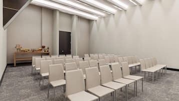 A conference room with rows of chairs, a wooden bench with items, and a door.
