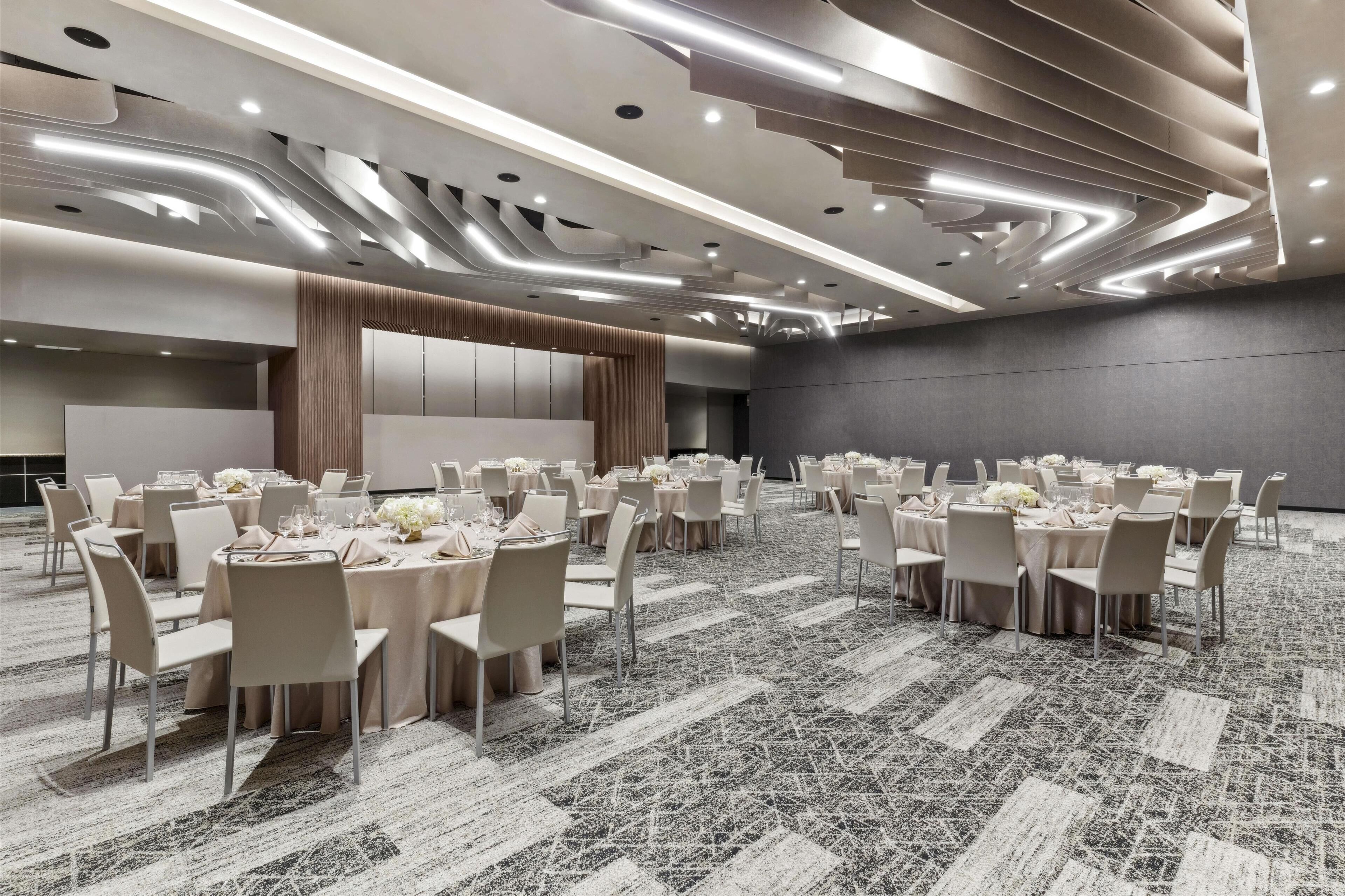 A conference room with round tables, chairs, and a stage.