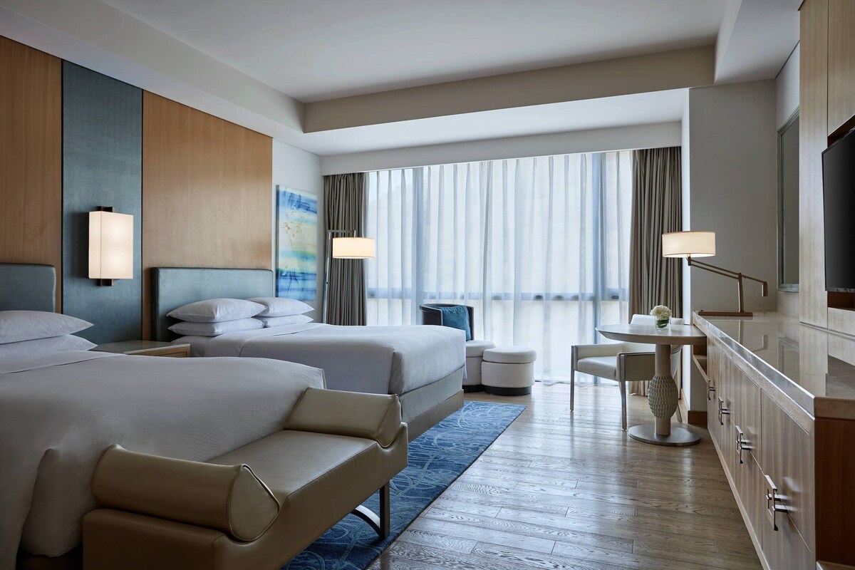 Habitación de hotel con dos camas, zona de comedor y televisor.