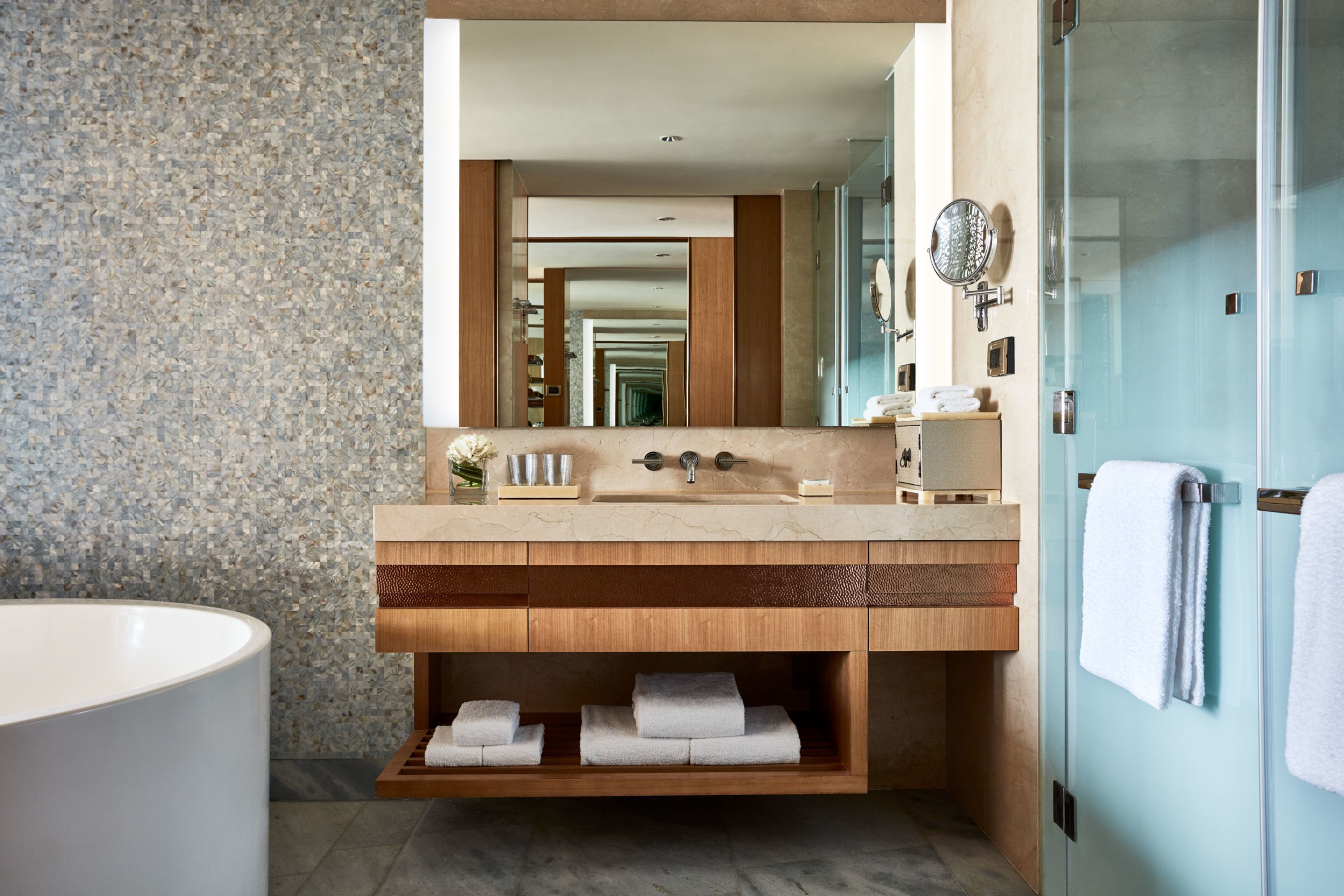 A modern bathroom with a freestanding bathtub, a large mirror, and a vanity with a marble countertop.
