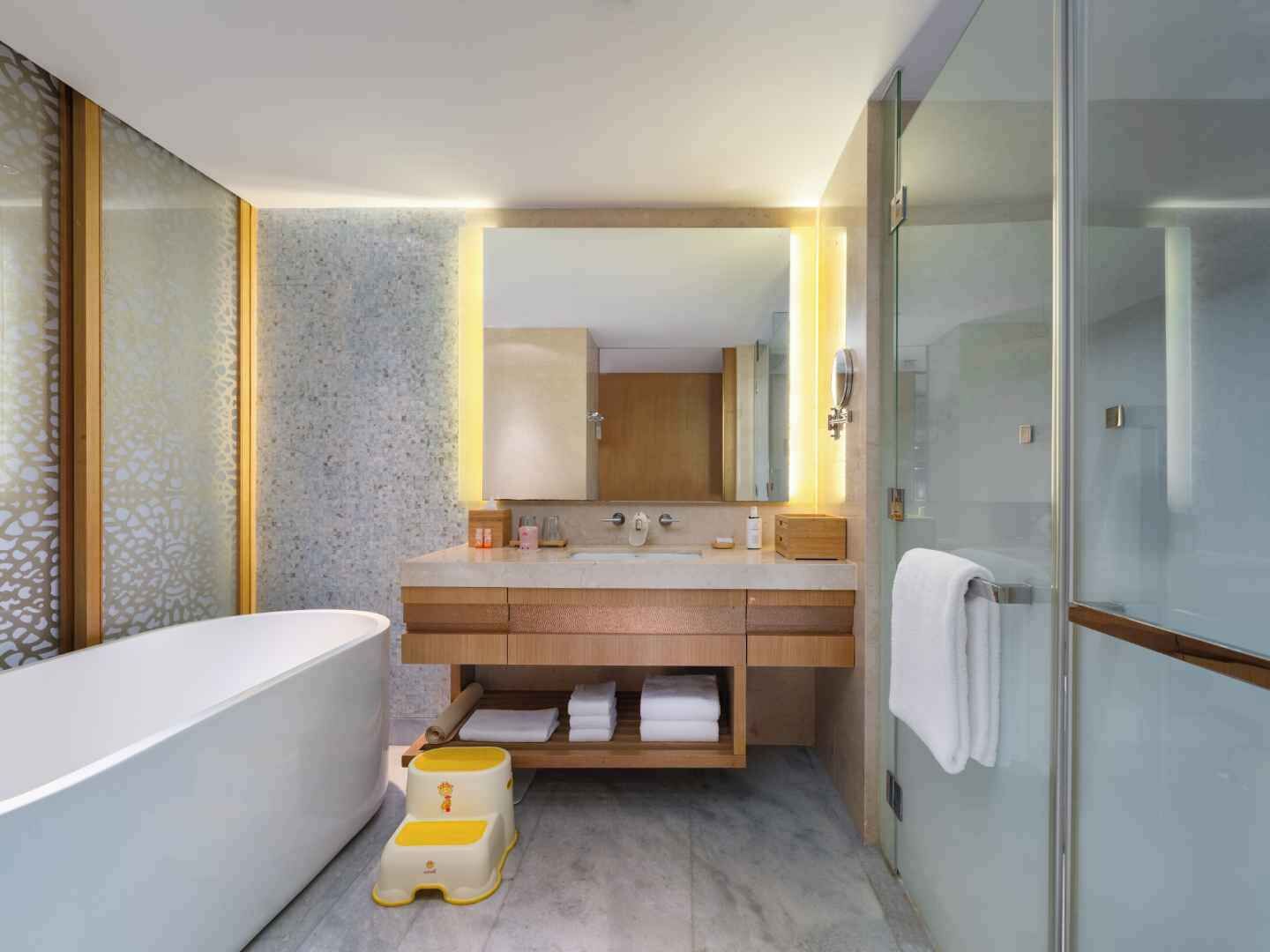 Ein modernes Badezimmer mit Badewanne, Waschtisch inklusive Spiegel und Duschbereich.