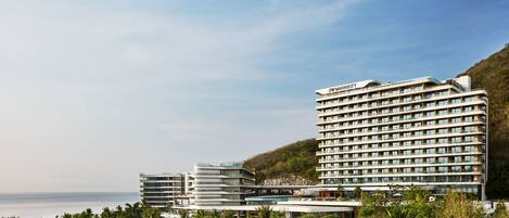 A JW Marriott hotel with multiple buildings, a pool area, and a view of the ocean.