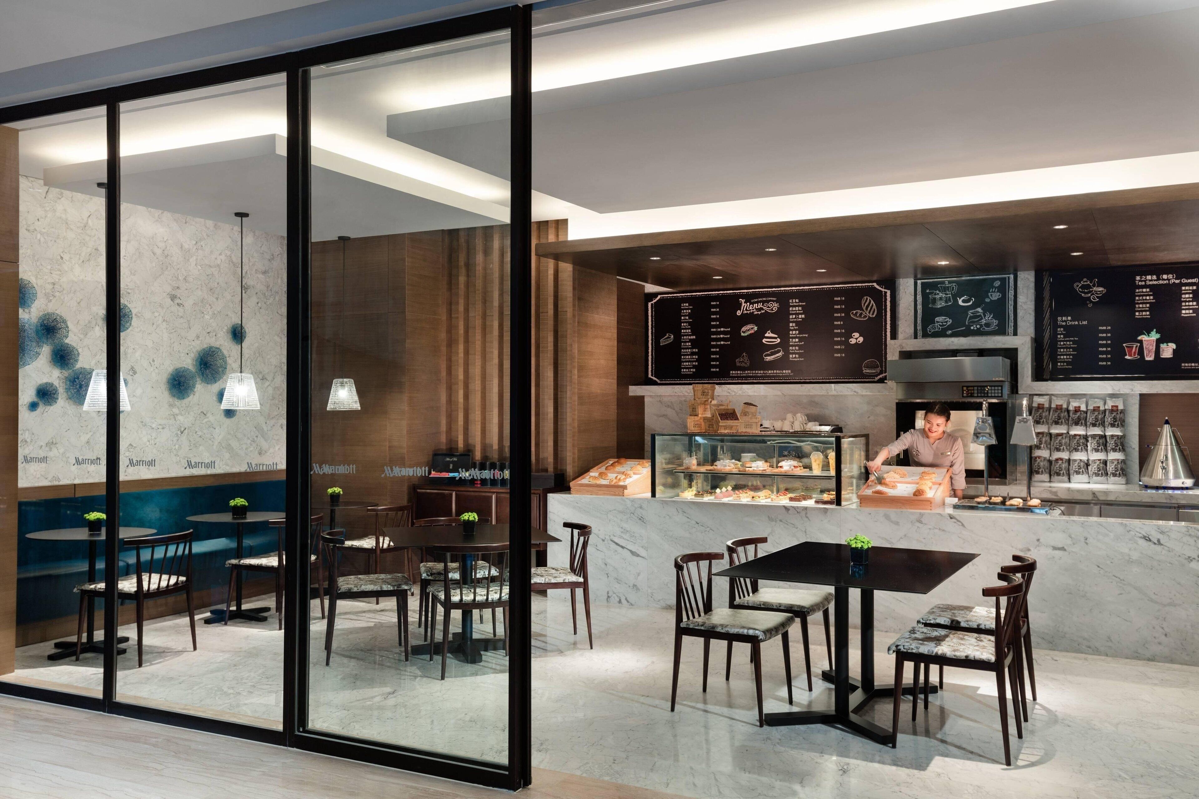 A modern restaurant with a marble counter, menu boards, and seating areas.