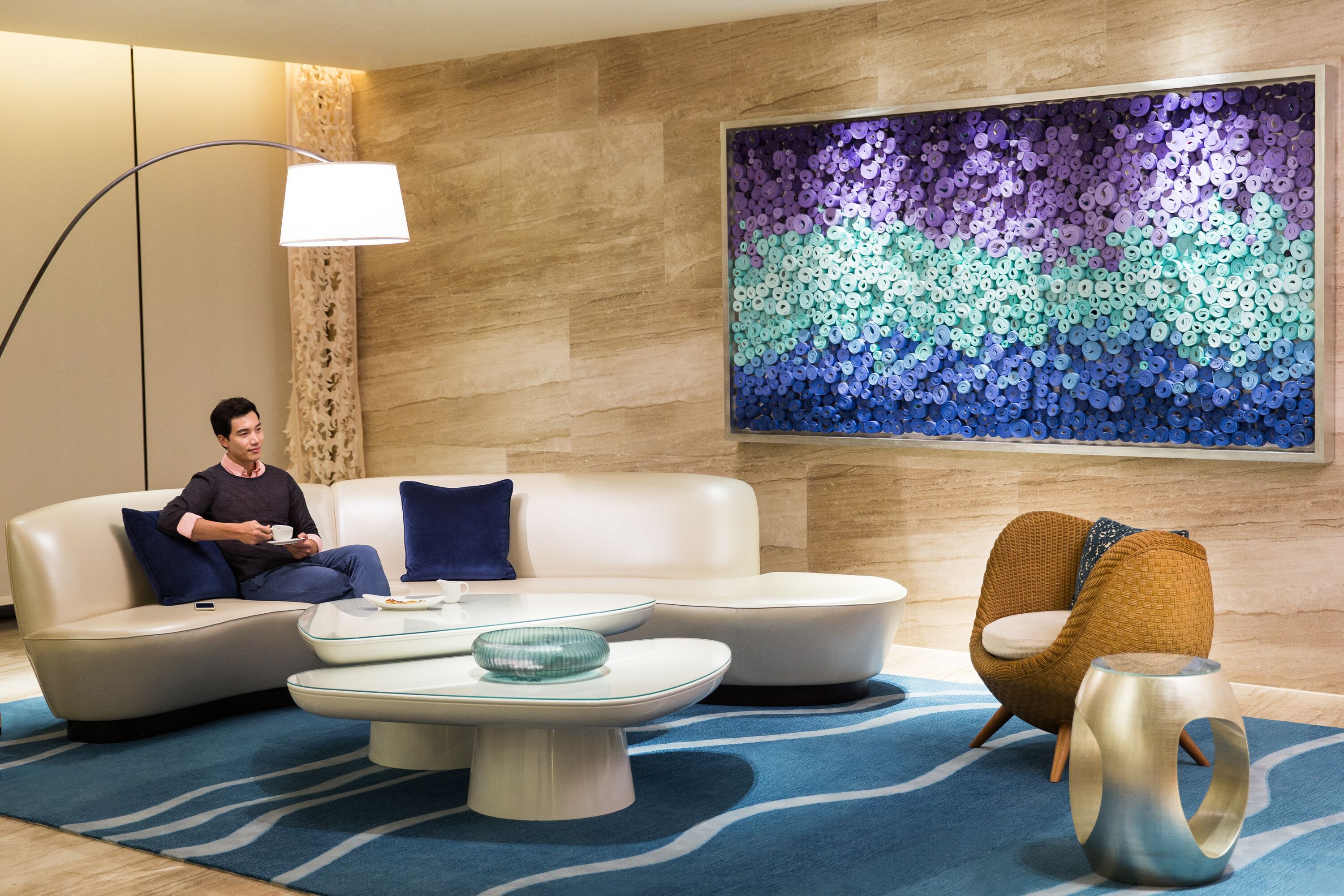 A modern living room with a sofa, a coffee table, a chair, and a wall art piece.