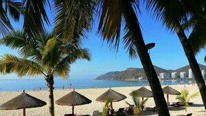 Una playa con palmeras, sombrillas y tumbonas.