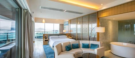 A modern hotel room with a large bed, a sofa, a round table, and a bathtub.