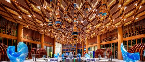 A spacious lobby with a high ceiling, modern chandeliers, and distinctive blue sculptures.