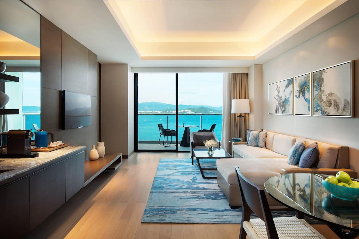 A modern living room with a sofa, coffee table, and a view of the sea.