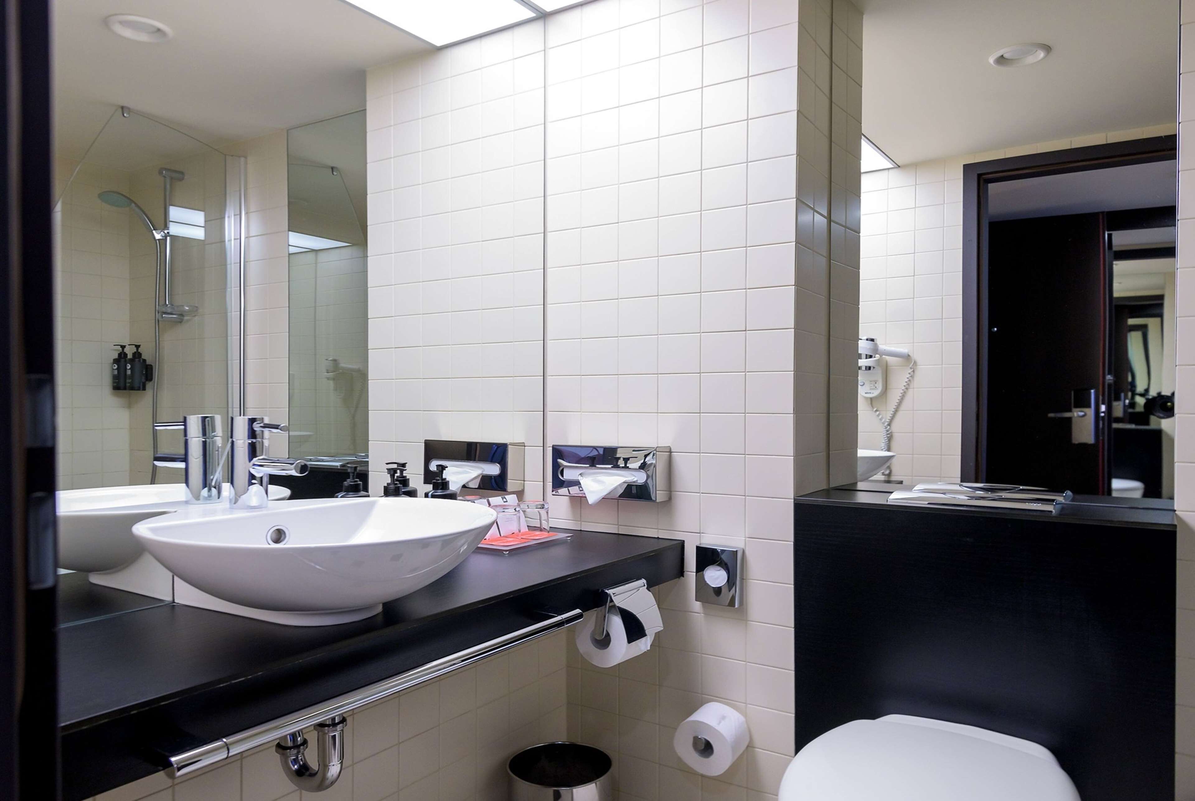 Un baño moderno con un lavamanos grande, espejo y un área de inodoro separada.