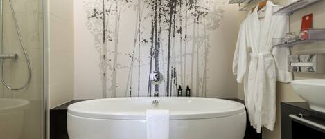 A modern bathroom with a large bathtub, a glass shower enclosure, and a wall-mounted towel rack.