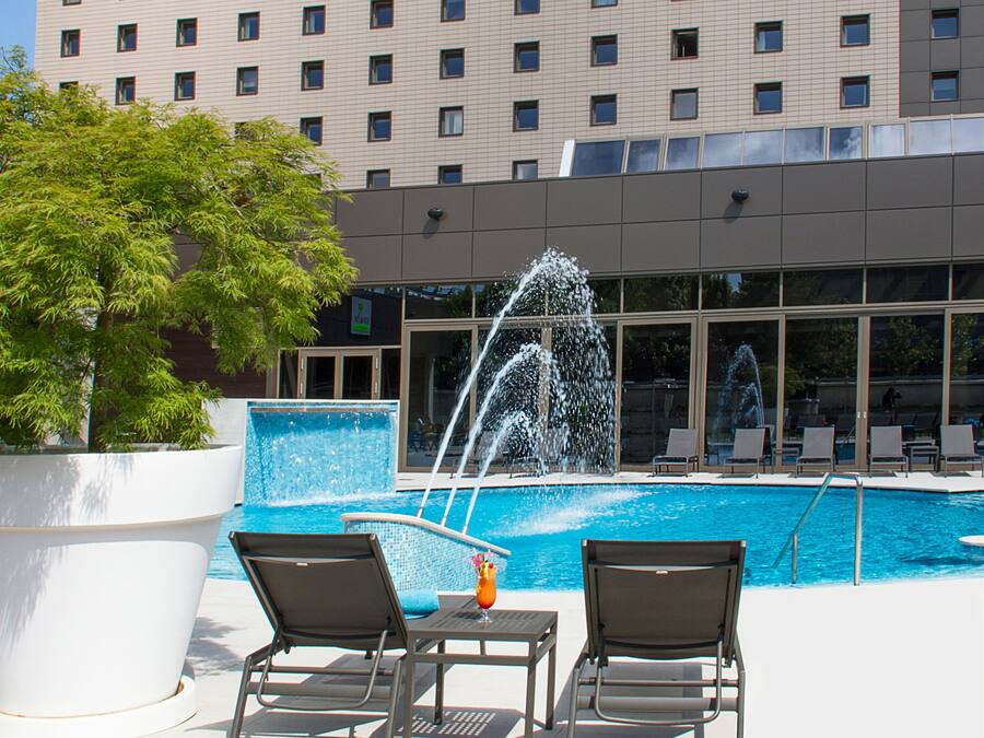 Un hotel con piscina, dos sillones de descanso y una fuente.