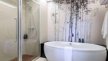 Ein modernes Badezimmer mit einer Glaskabine zur Dusche, einer freistehenden Badewanne und einem wandmontierten Waschbecken.