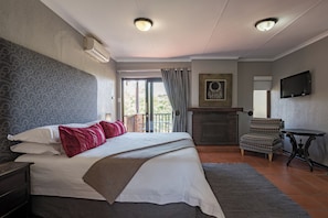 A bedroom with a large bed, a chair, a television, and a fireplace.