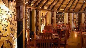 A traditional wooden interior with a thatched roof, wooden furniture, and decorative carvings. - Greenway Woods Resort (Mbombela)