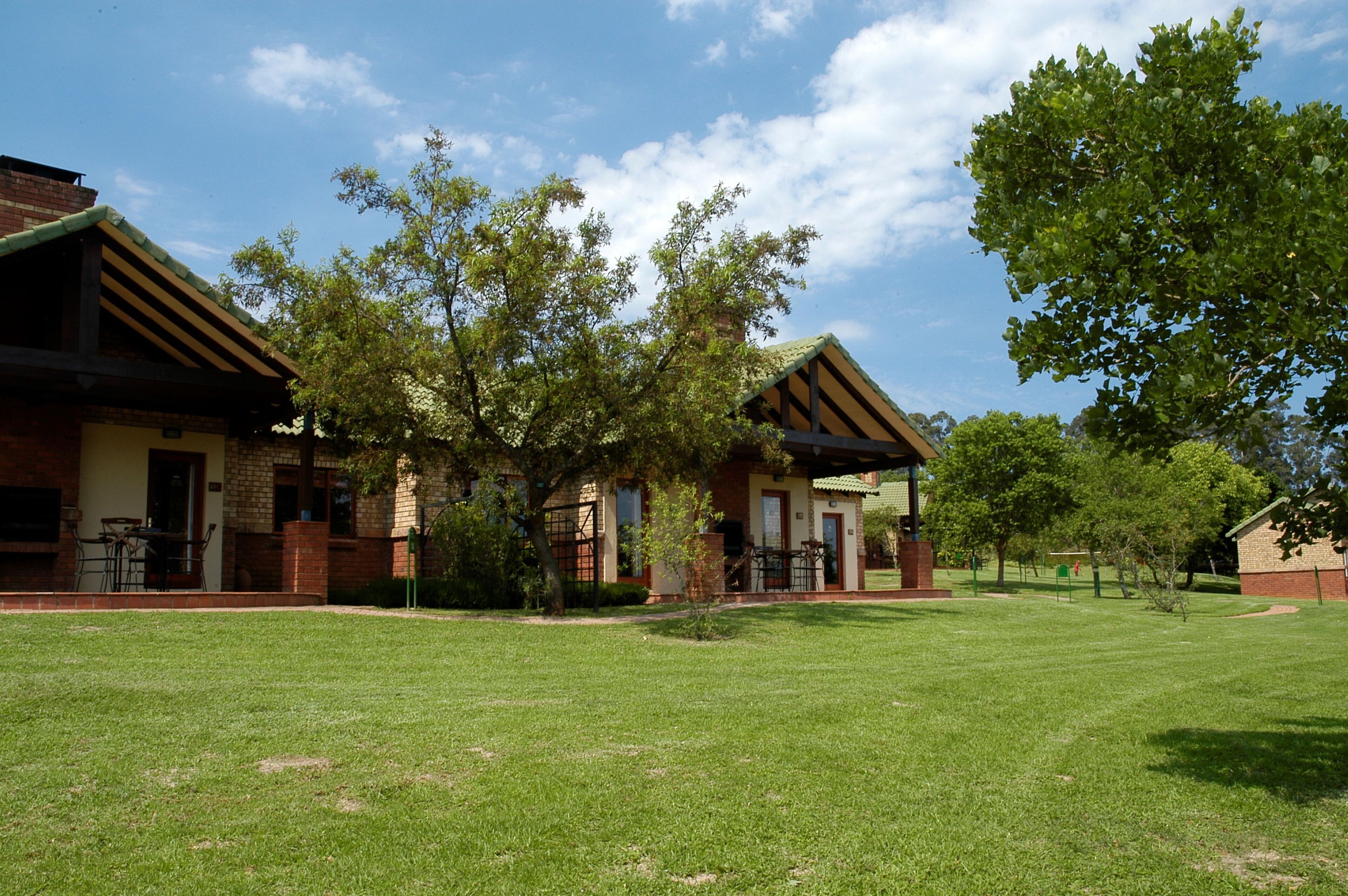 A building with a brick facade, a covered patio area, and a well-maintained lawn.