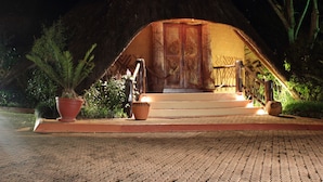 A thatched-roof structure with a wooden door and steps leading up to it. - Greenway Woods Resort (Mbombela)