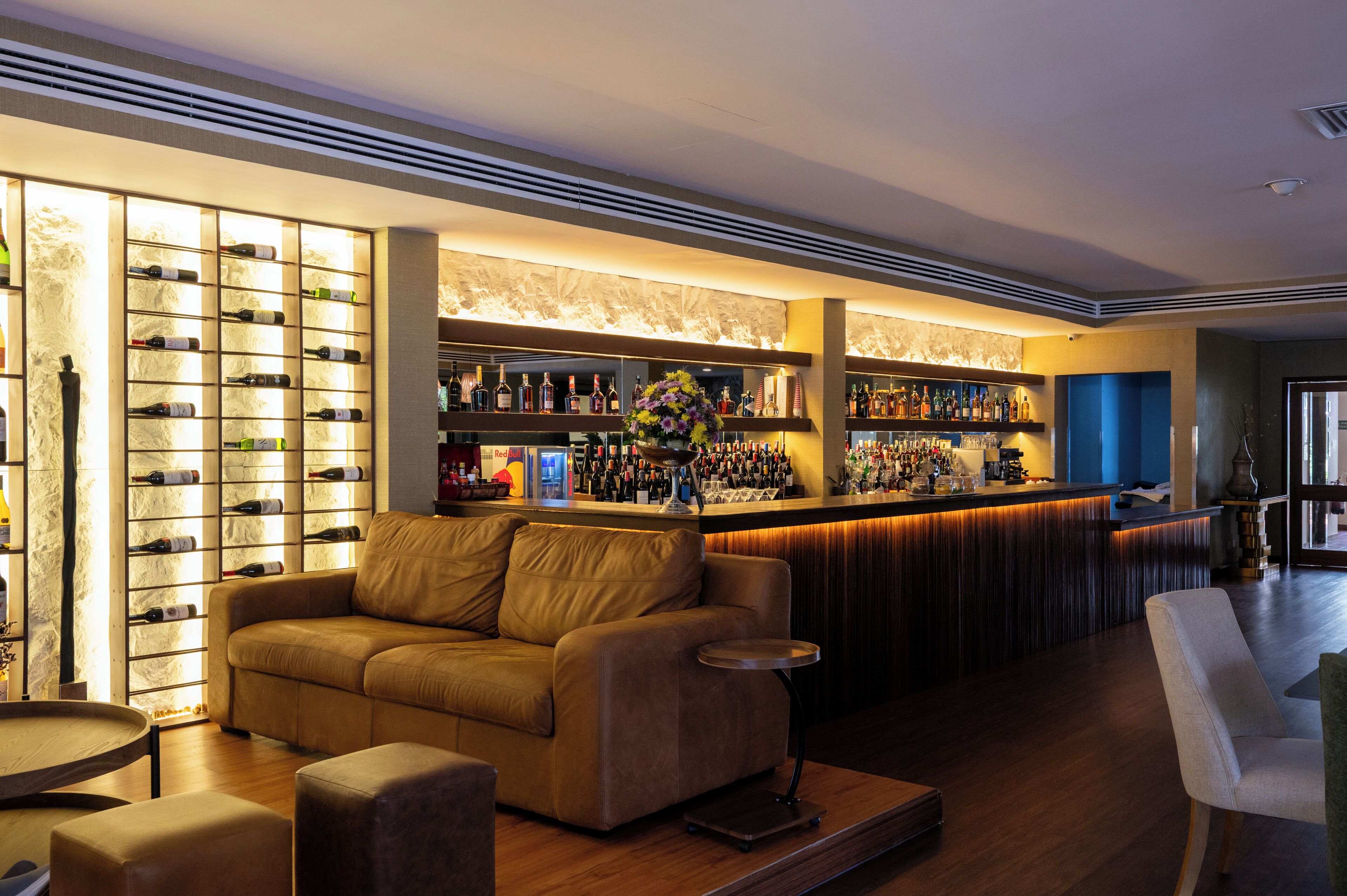 Una zona de bar con un sofá, una mesita redonda y una vitrina para vinos.