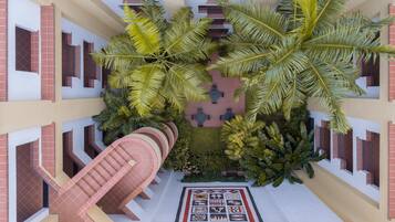 Un atrio de varios niveles con un patio central, que cuenta con una escalera en espiral, asientos al aire libre y exuberantes plantas tropicales.