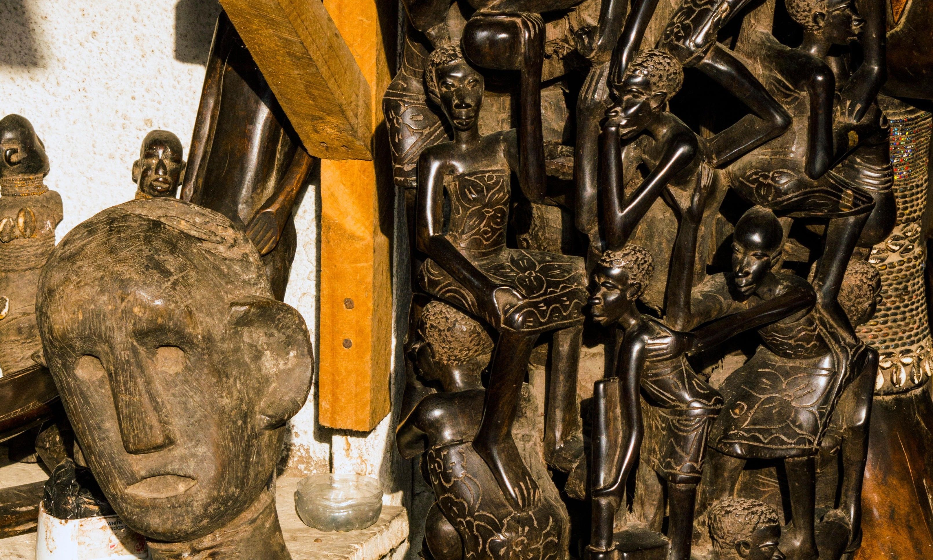 A collection of wooden sculptures and carvings, including a prominent carved head and various figures.