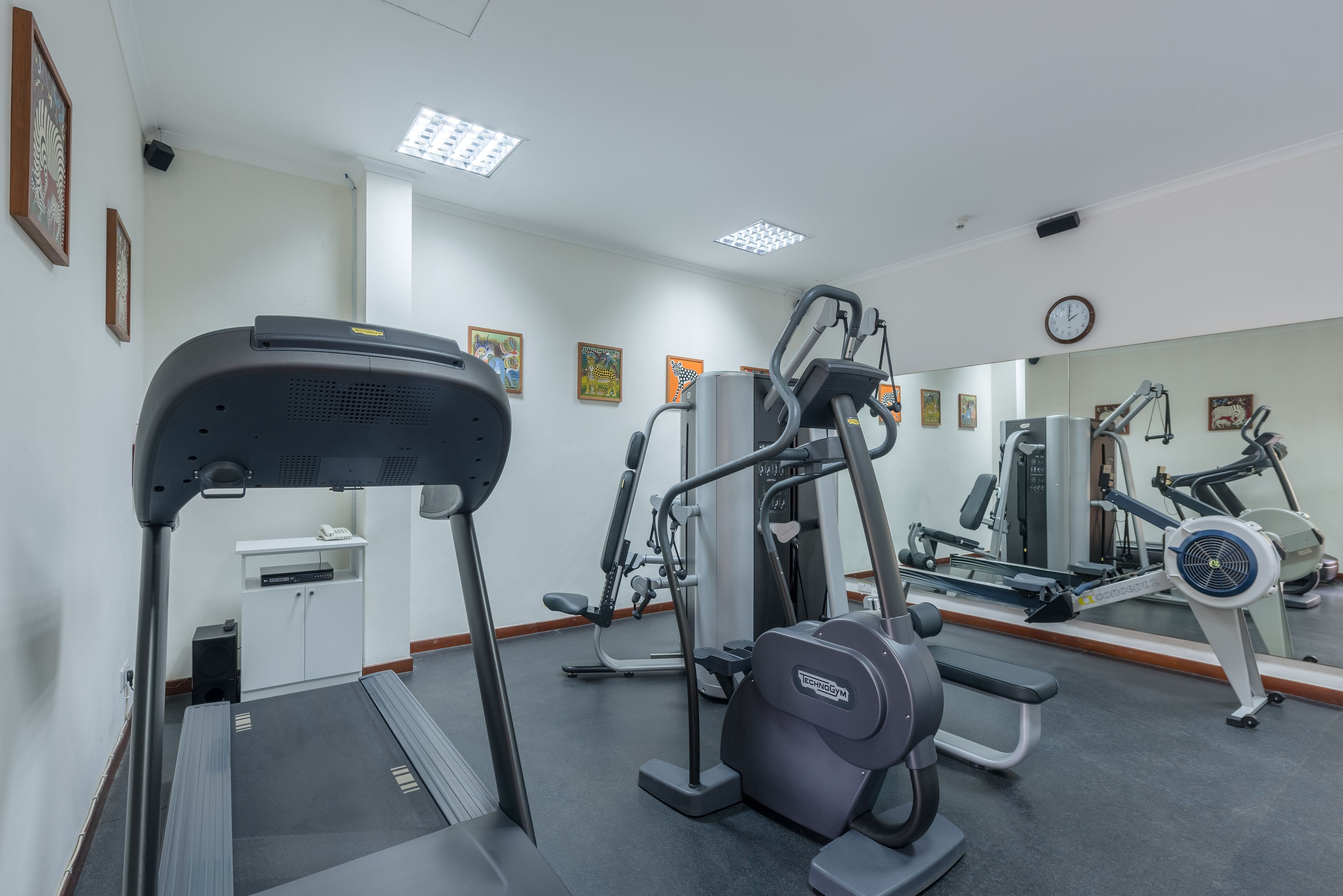 Un gimnasio con cintas de correr, elípticas y equipo de pesas.