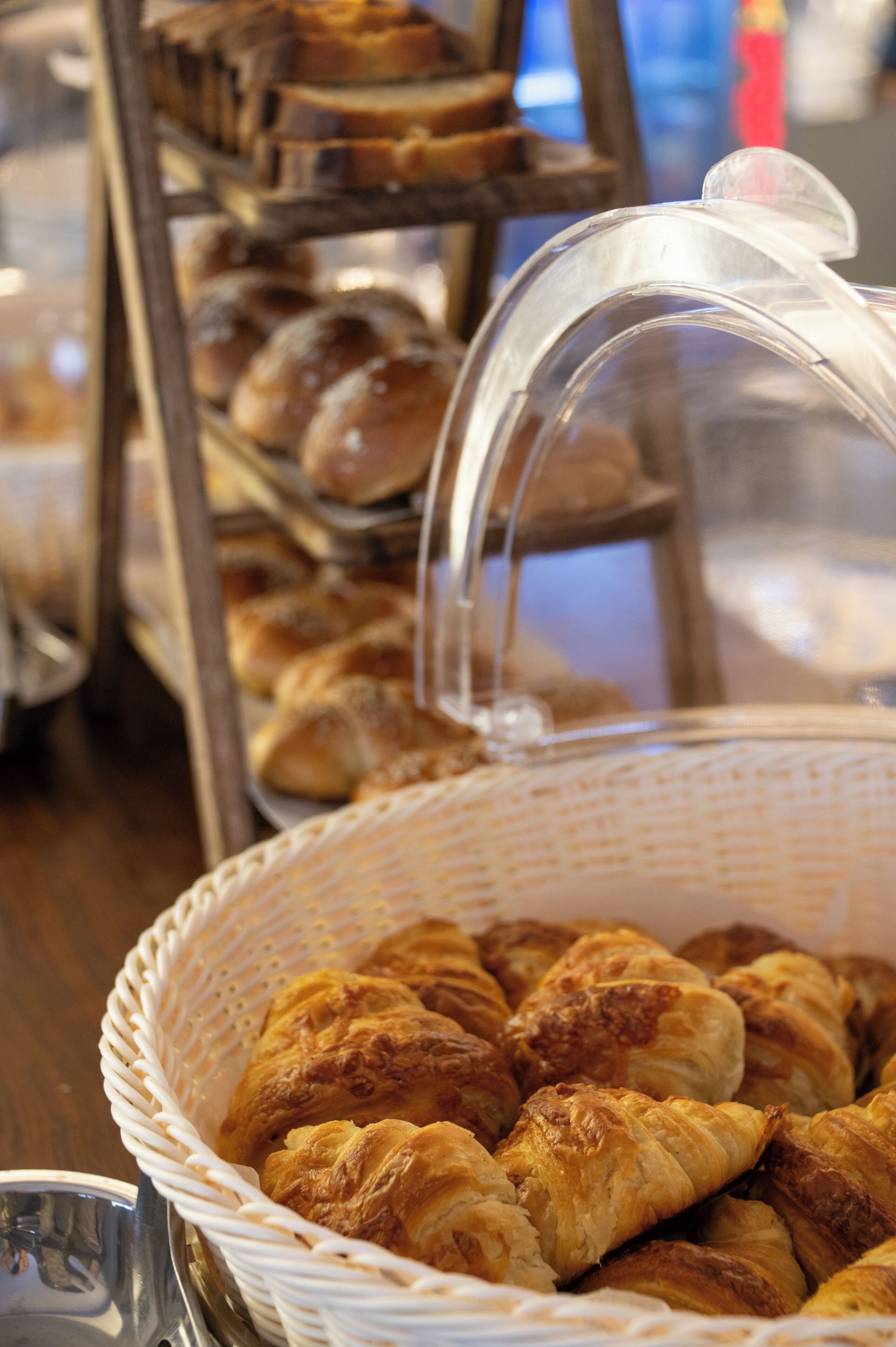 A basket of croissants and a display case with various baked goods.