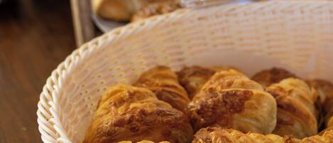 A basket of croissants and a display case with various baked goods.