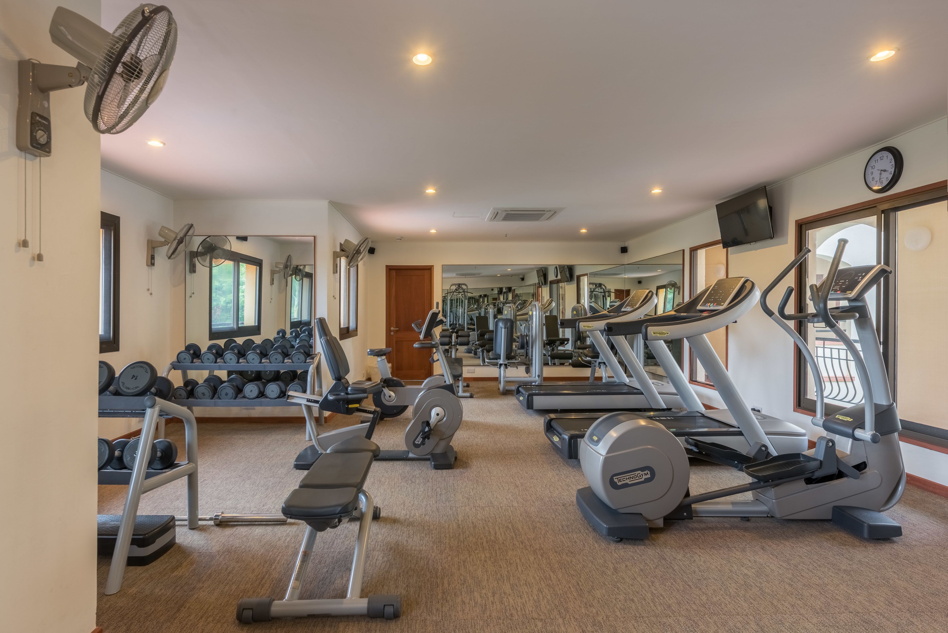 Un gimnasio con cintas de correr, elípticas y bancos de pesas.