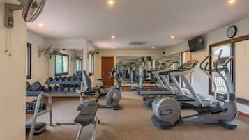 Un gimnasio con cintas de correr, elípticas y bancos de pesas.