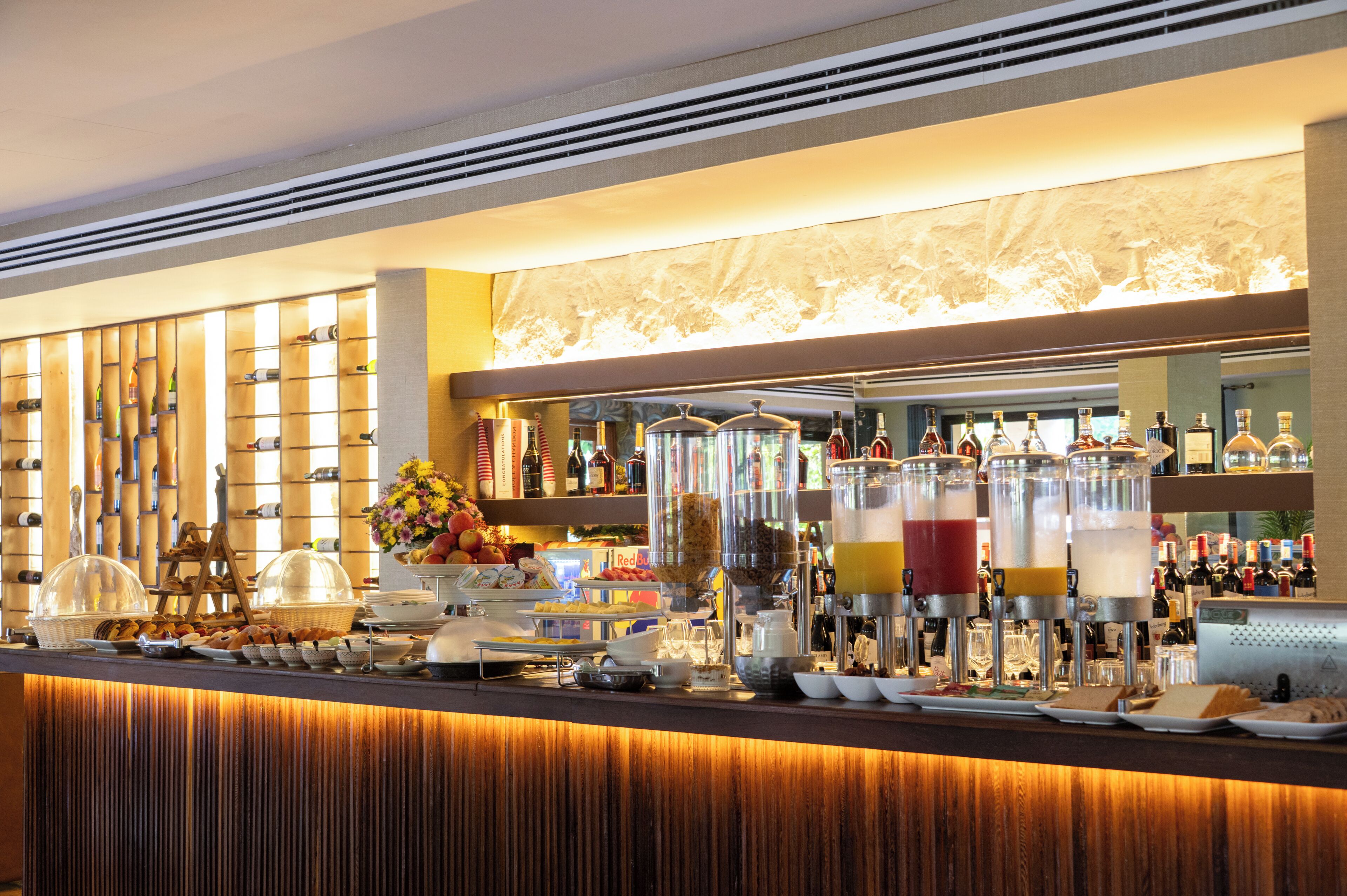 Una barra de buffet con diferentes alimentos, bebidas y una selección de botellas.